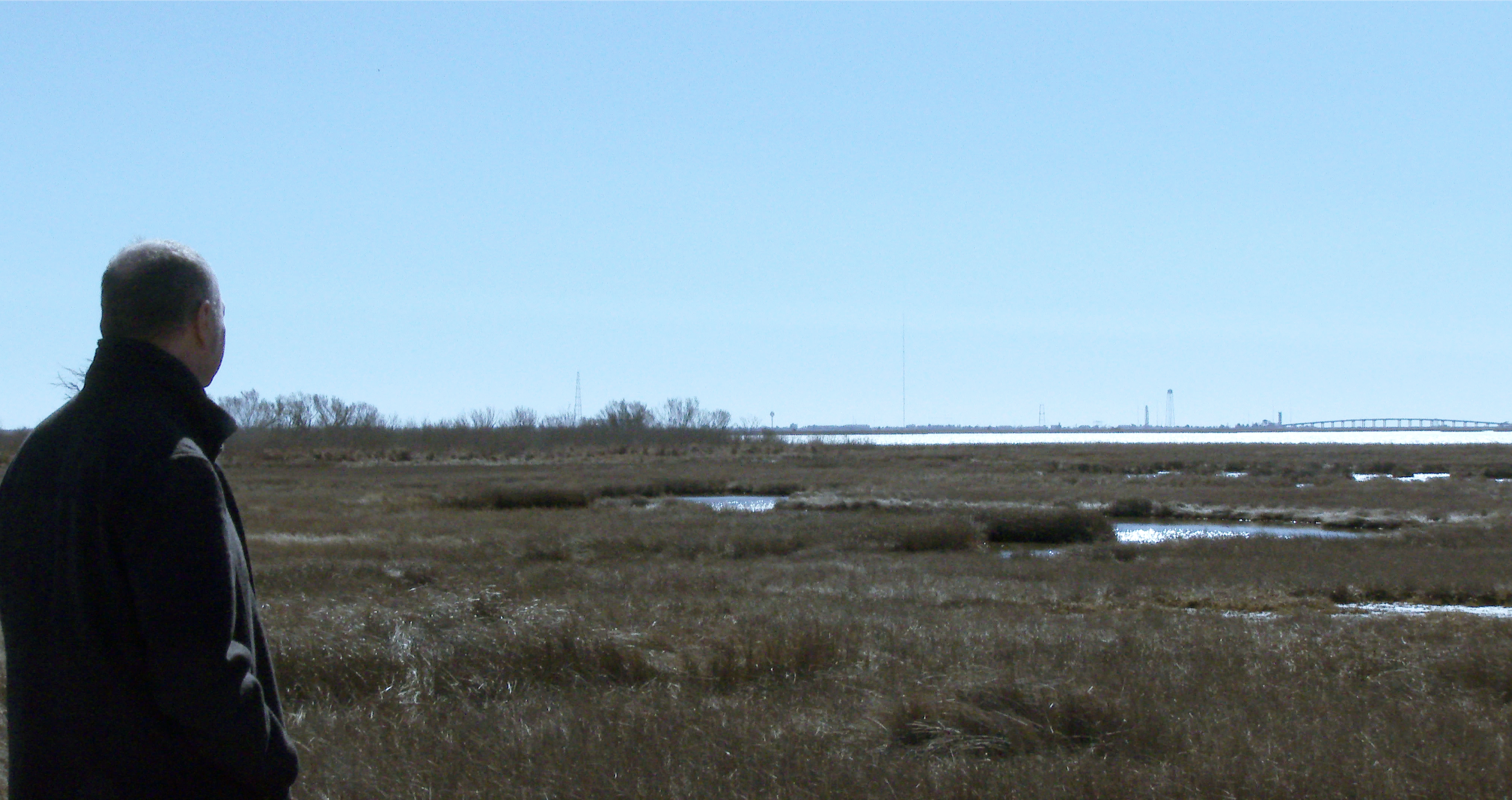 Eduardo Kac waiting for the Antares230+ rocket (in the background, to the left of the water tower) to liftoff from the Mid-Atlantic Regional Spaceport's Pad-0A at NASA's Wallops Flight Facility on Wallops Island, Virginia